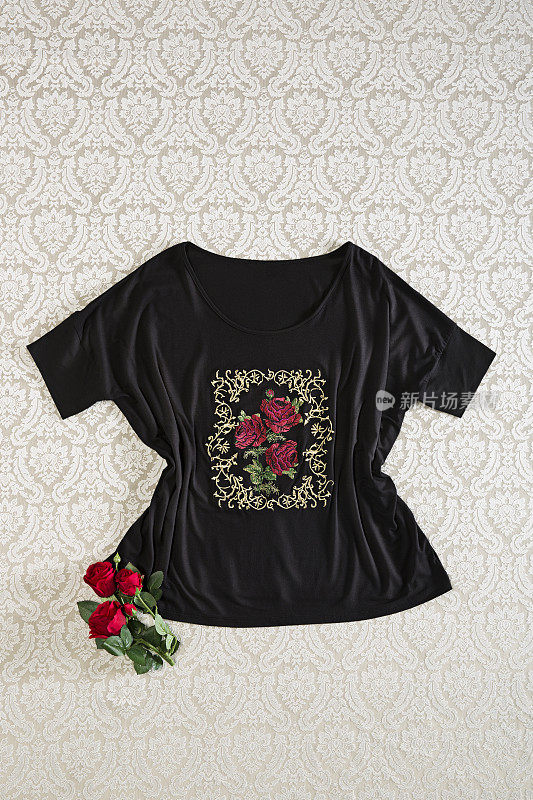 Fashionable black blouse with red roses isolated on wallpaper background